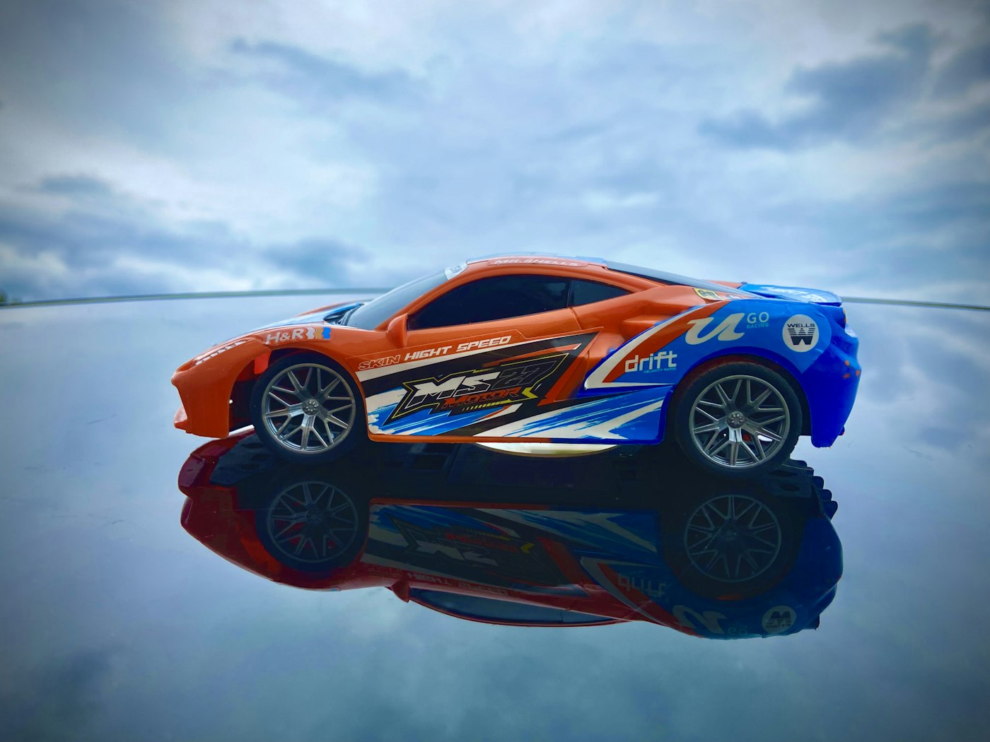 Orange and blue drift RC car on a reflective surface